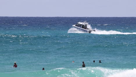 a speedboat moves past people swimming in the sea.