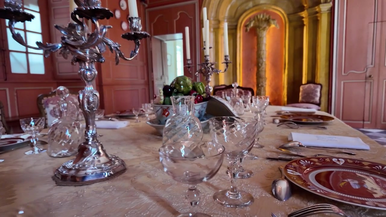 Pemandangan gerak lambat ruang makan formal yang elegan di Château de Villandry, menampilkan meja yang tertata indah dengan peralatan gelas kristal, kandil perak, dan interior Renaisans di Lembah Loire