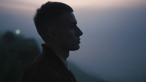 peaceful man looking mountain landscape. dreamy guy standing on rock