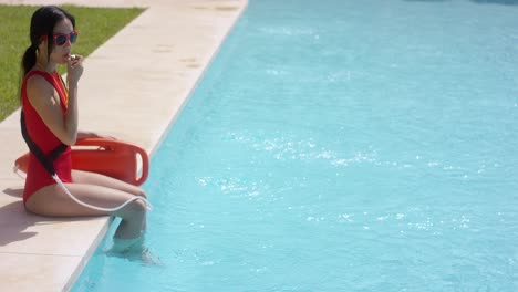 Lifeguard-using-whistle-while-sitting-in-pool