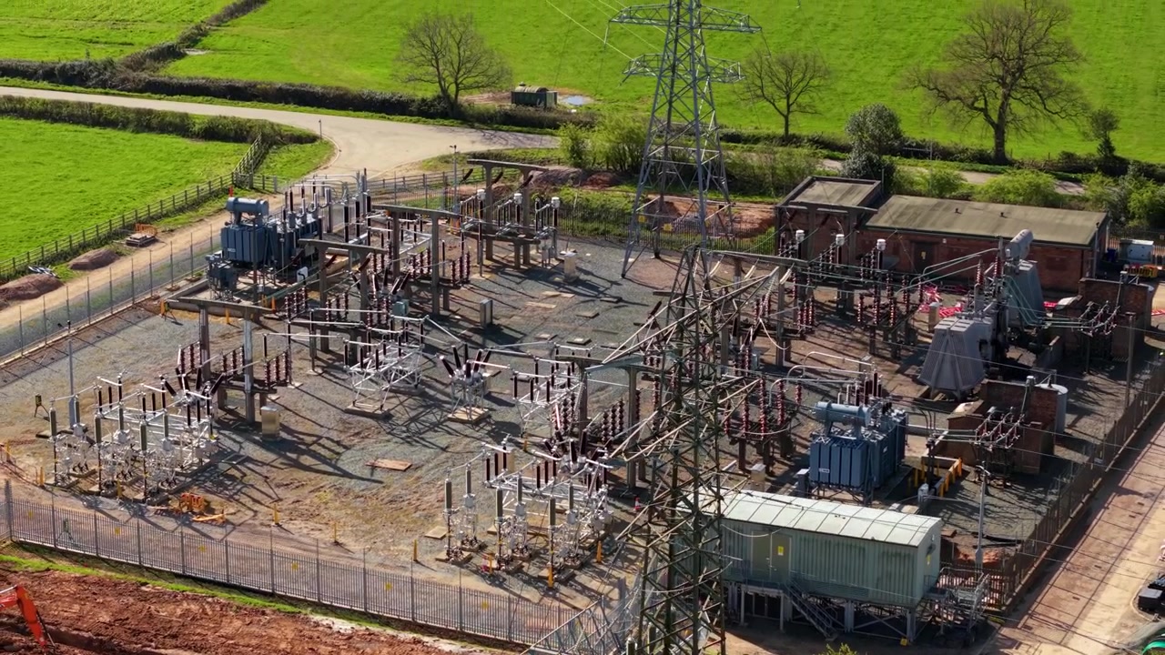 Drohnenaufnahme über einer kompakten Stromverteilungsstation und einem Transformatorenfeld