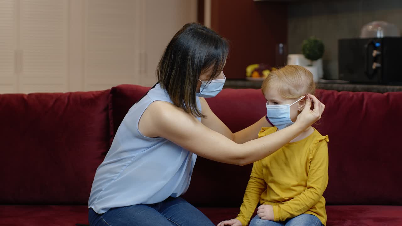 엄마가 아픈 어린 딸을 보호하는 의료 마스크를 집에서 착용합니다. 코로나바이러스 격리 봉쇄