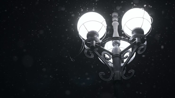 Lampione stradale in una notte invernale. Lanterna cittadina nella neve che cade a Natale.