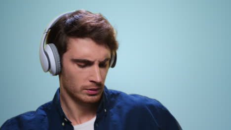 Man-dancing-in-headphones-on-blue-background.-Guy-listening-music-in-earphones