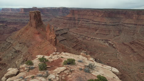 drone shot of person walking on top of hill above abyss and canyon