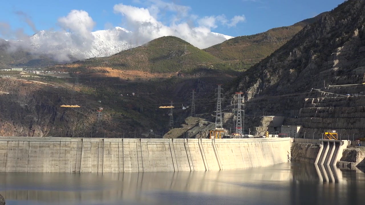 Stor betondæmning og vandreservoir i bjergrigt landskab