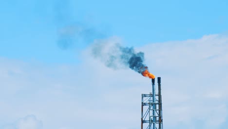 black, polluting smog pouring out from the top of an industrial refinery into a beautiful, clear blue sky in curacao