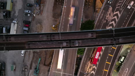 slowly rising aerial shot over trains crossing over busy traffic conjunction of commuting trucks and cars