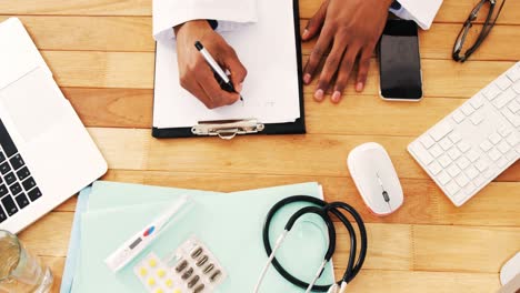 handen van een dokter die op een klembord schrijft