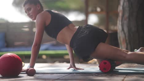 woman doing outdoor fitness exercise routine with foam roller and yoga ball