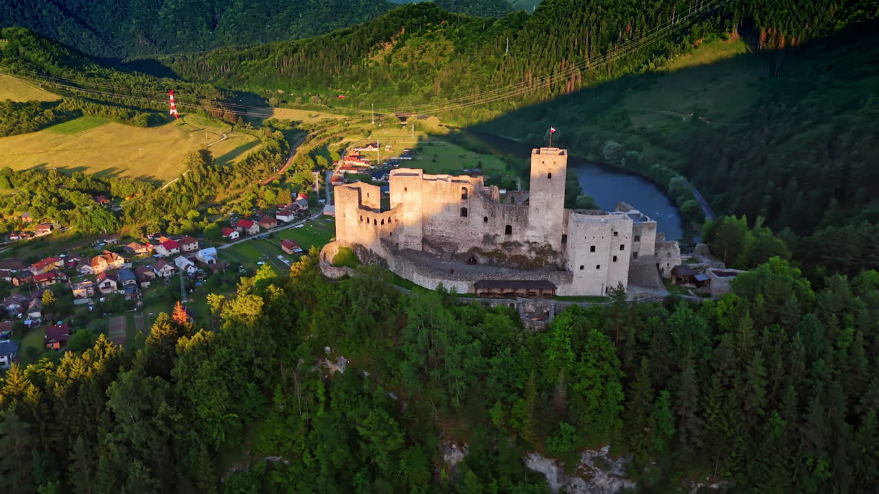 Scenic castle atop a mountain landscape. Ancient castle sits on a rocky hill, surrounded by lush greenery and a peaceful village under a clear blue sky