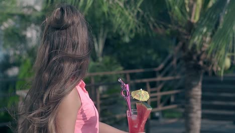 pretty brunette in pink blouse holds cocktail with straws