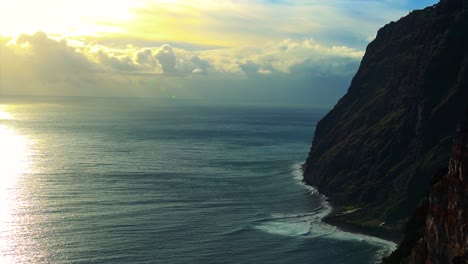 footage of a cliff next to the sea and the horizon on the background in a sunny day with some clouds