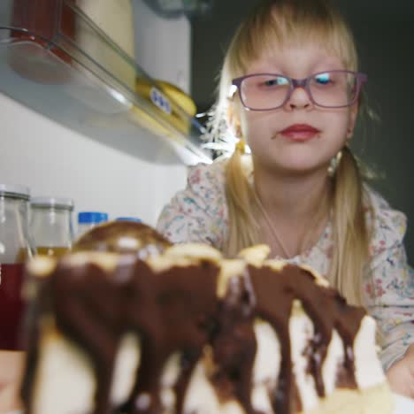 a little girl secretly tastes the cake in the fridge