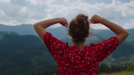 unrecognizable girl raising hands watching beautiful mountains closeup back view