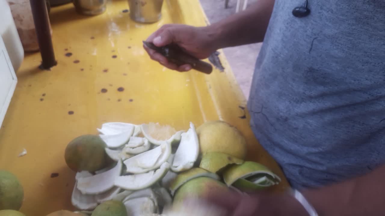 primer plano joven pelando mosambi para hacer jugo en el mercado callejero local