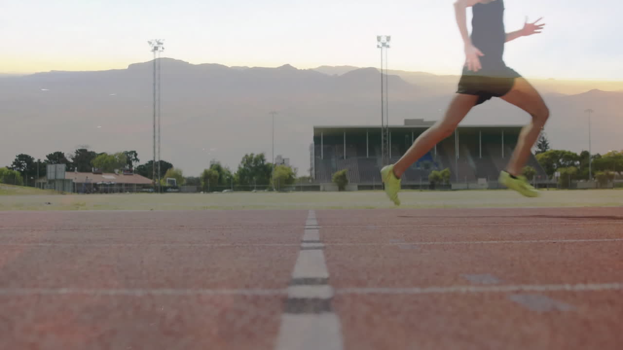 Sprinting on track, runner with stadium and mountains in background