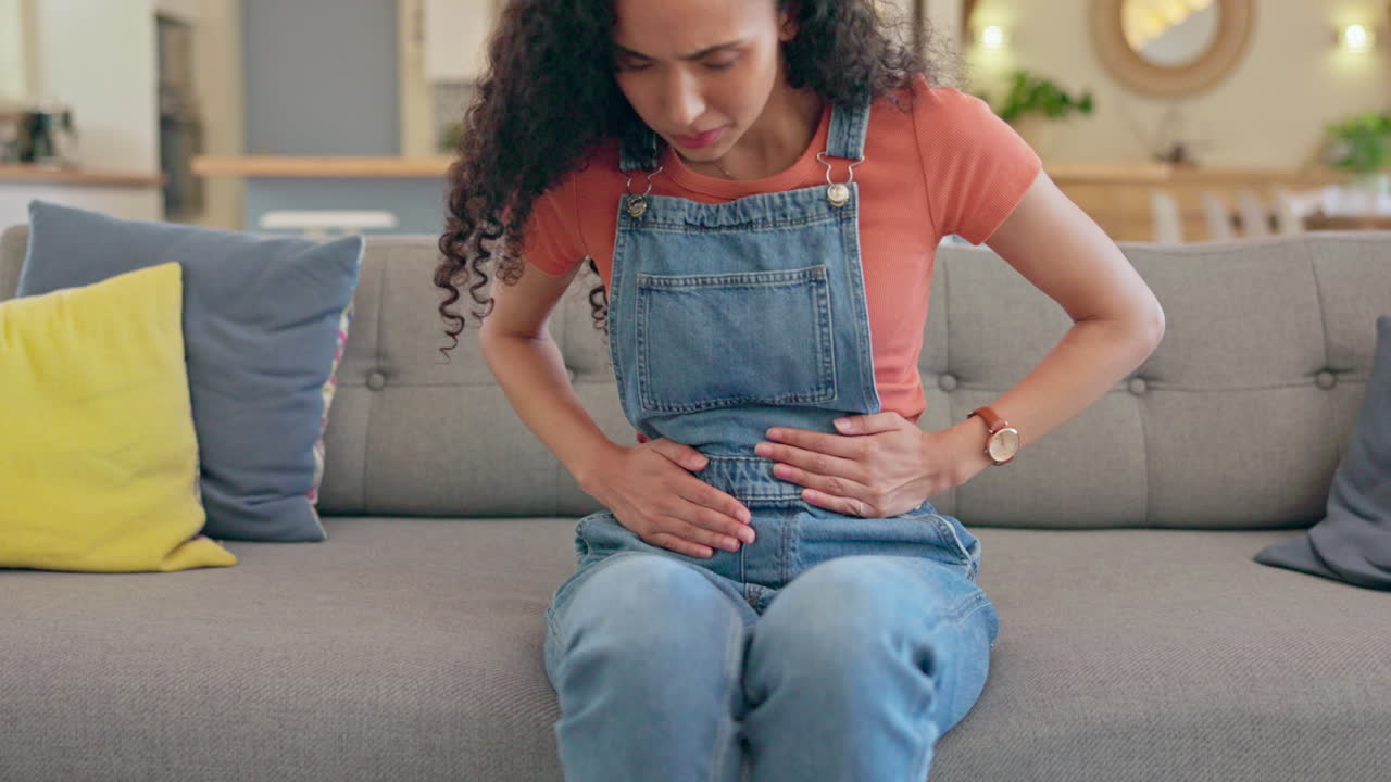 Sick woman, stomach ache and pain on sofa