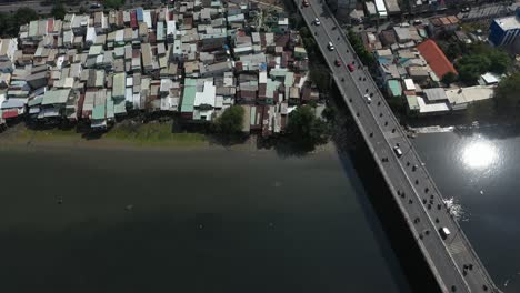 toma aérea sobre un puente de tráfico ocupado y casas de chabolas frente al mar a lo largo del canal kenh te en la ciudad de ho chi minh, vietnam en un día soleado