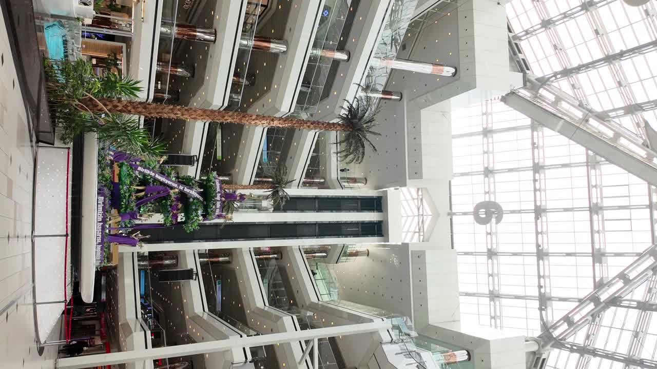 Multi-level Modern Shopping Mall Interior with Palm Trees and Glass Ceiling