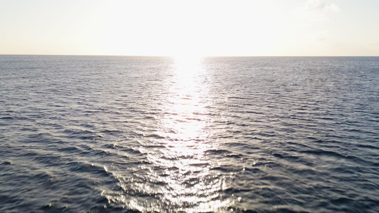 바다 물 표면을 가로질러 반사되는 빛의 번개로 해가 지는 곳으로 공중 돌리