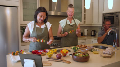 diverse women preparing colorful vegetable skewers in kitchen, enjoying cooking together, at home