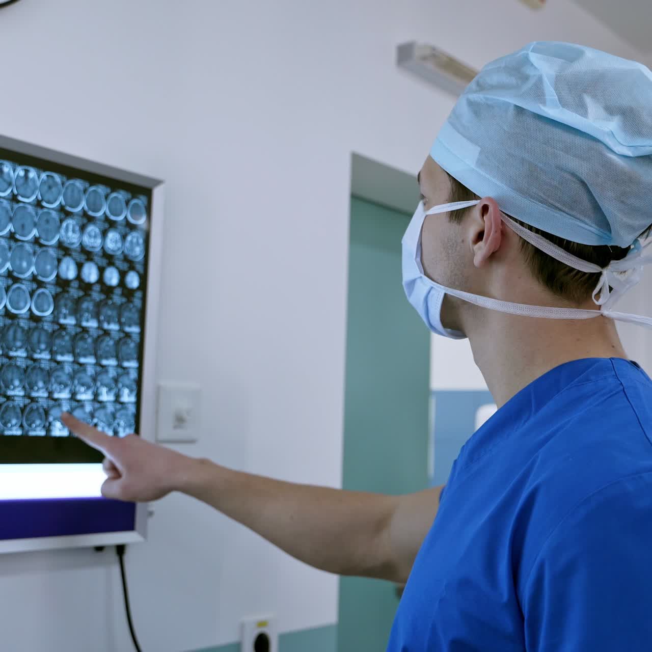Surgeon in medical uniform with mask looking at x-ray image. Doctor analyzing test results on a whiteboard in the operating room.