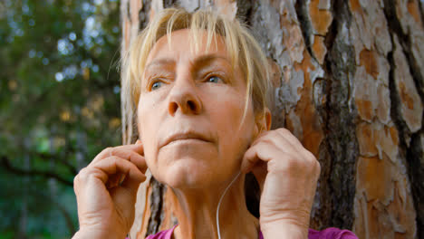 Senior-woman-leaning-on-a-tree-and-listening-music-4k