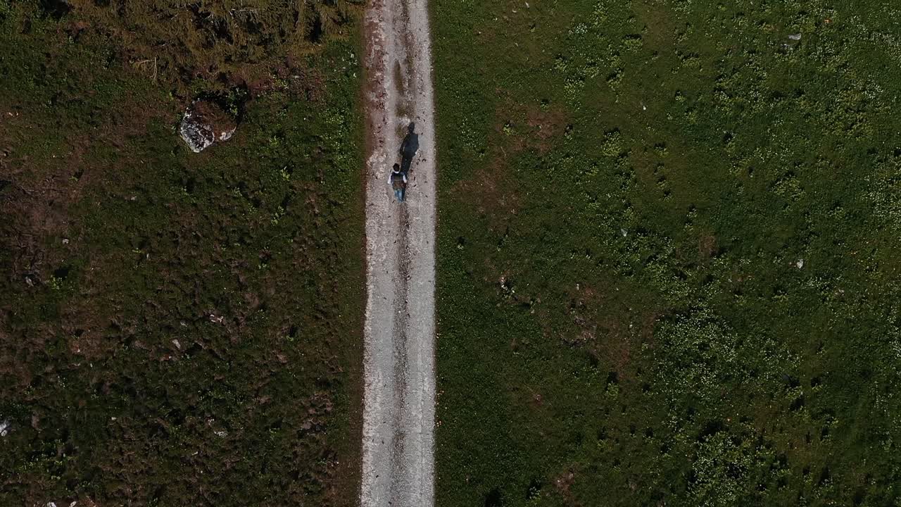 Ripresa aerea dall'alto di un escursionista che fa trekking su una strada sterrata di campagna.