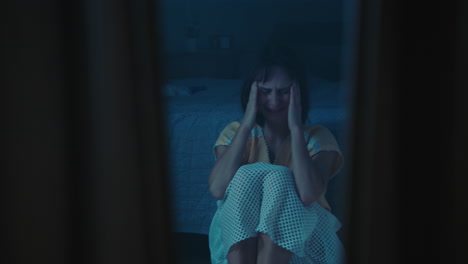 a traumatised and disoriented girl sits on the bedroom floor