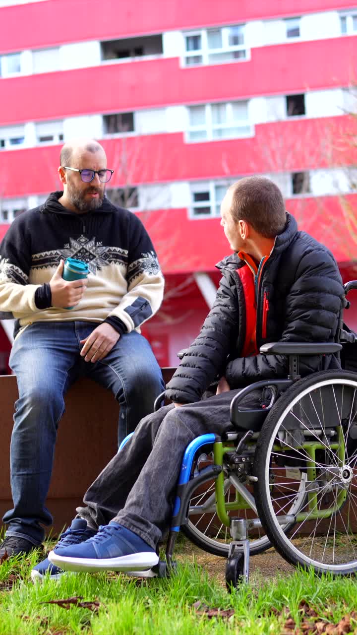 Due uomini che parlano, uno su una sedia a rotelle