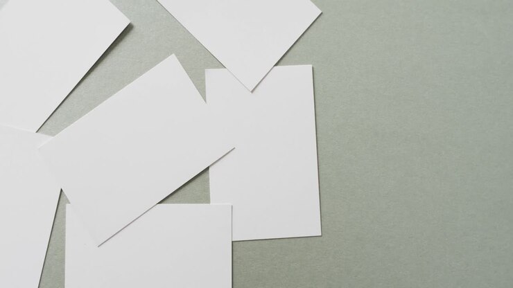 Multiple blank white business cards on green background, copy space, slow motion