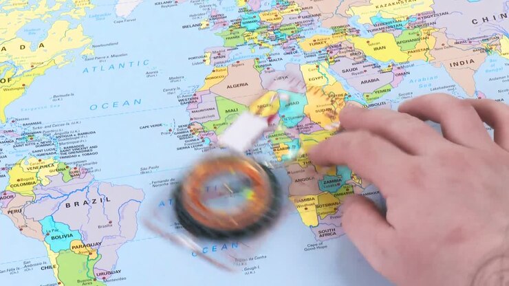 Mano che muove una bussola su una mappa del mondo