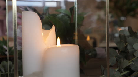 two candles burning in glass container with gum leaves, slow motion