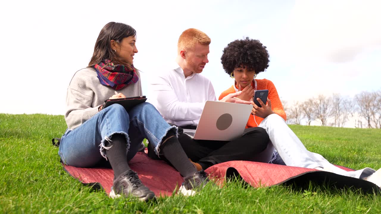 Group of people working outdoors on a laptop and mobile phone