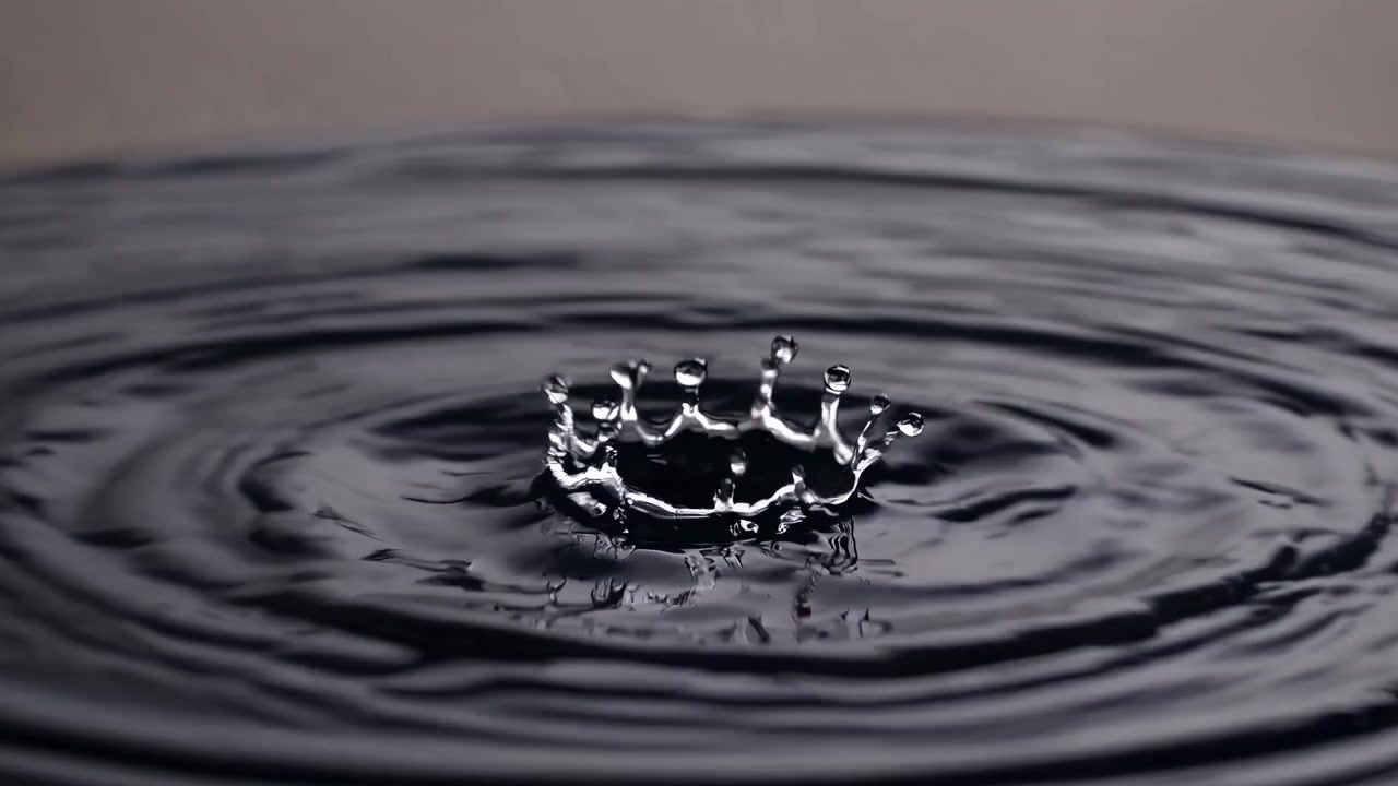 Water Drop Creating a Crown Splash in Dark Liquid