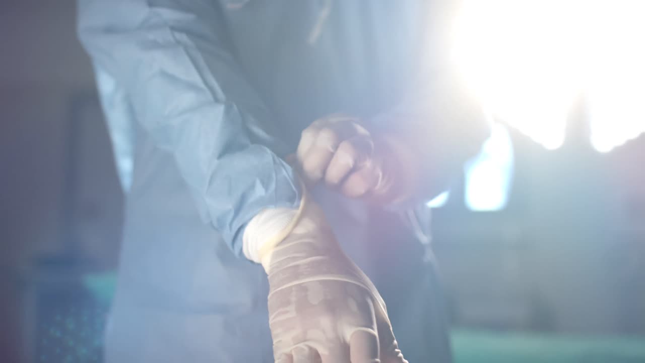 sección media de un cirujano afroamericano que usa guantes médicos en el quirófano, cámara lenta