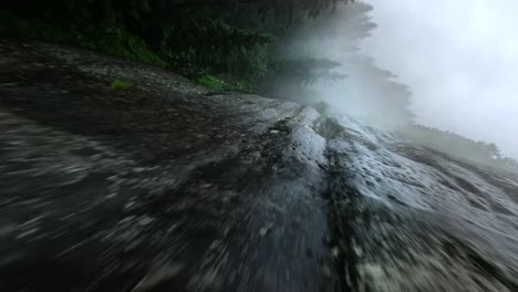 die fpv-drohne fliegt zwischen den bergen und wäldern und erkundet herrliche wasserfälle