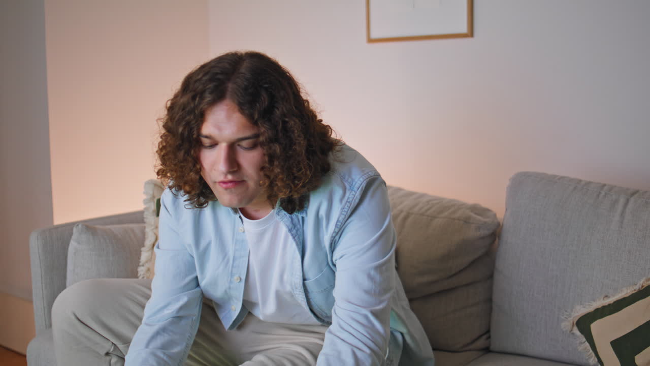 Serious man eating snacks on couch watching television alone closeup. Young male