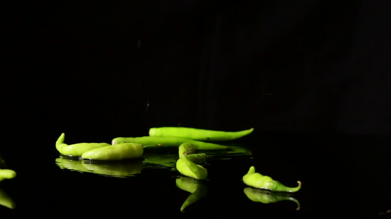 slow motion falling green chilli , water splash out