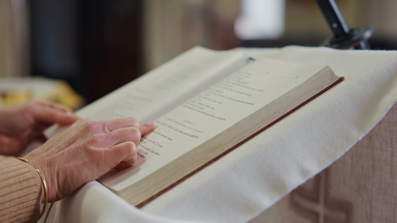 Mani femminili che sfogliano le pagine della sacra scrittura poste su un pulpito durante la messa cattolica. Donna in.