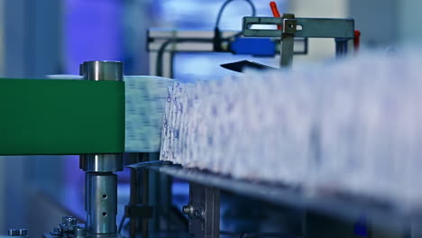 rotating rollers push already packed individual diapers to the conveyor. diapers put in a stack on the conveyor belt. close up.
