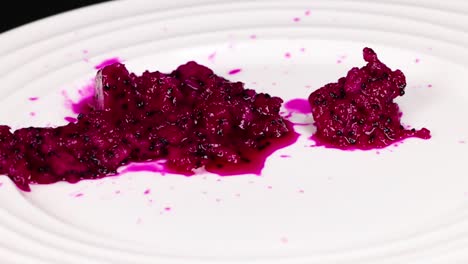 close-up of vibrant dragon fruit pulp spread across a white plate, highlighting its rich color and texture.