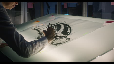 person sketching a design on a light table