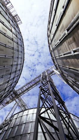 modern grain terminal. metal storage tanks for drying grain. industrial equipment for agribusiness. large grain elevators on blue sky background. close-up. vertical video