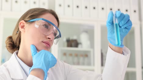 scientist woman analyzing blue liquid in test tube in lab