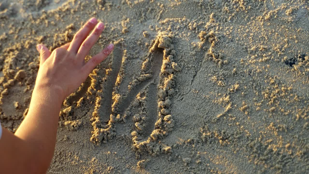 Inscription of handwritten on sand. Close up view of inscription of handwritten on sandy beach