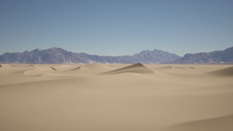 dunas de arena en el desierto con montañas en el fondo