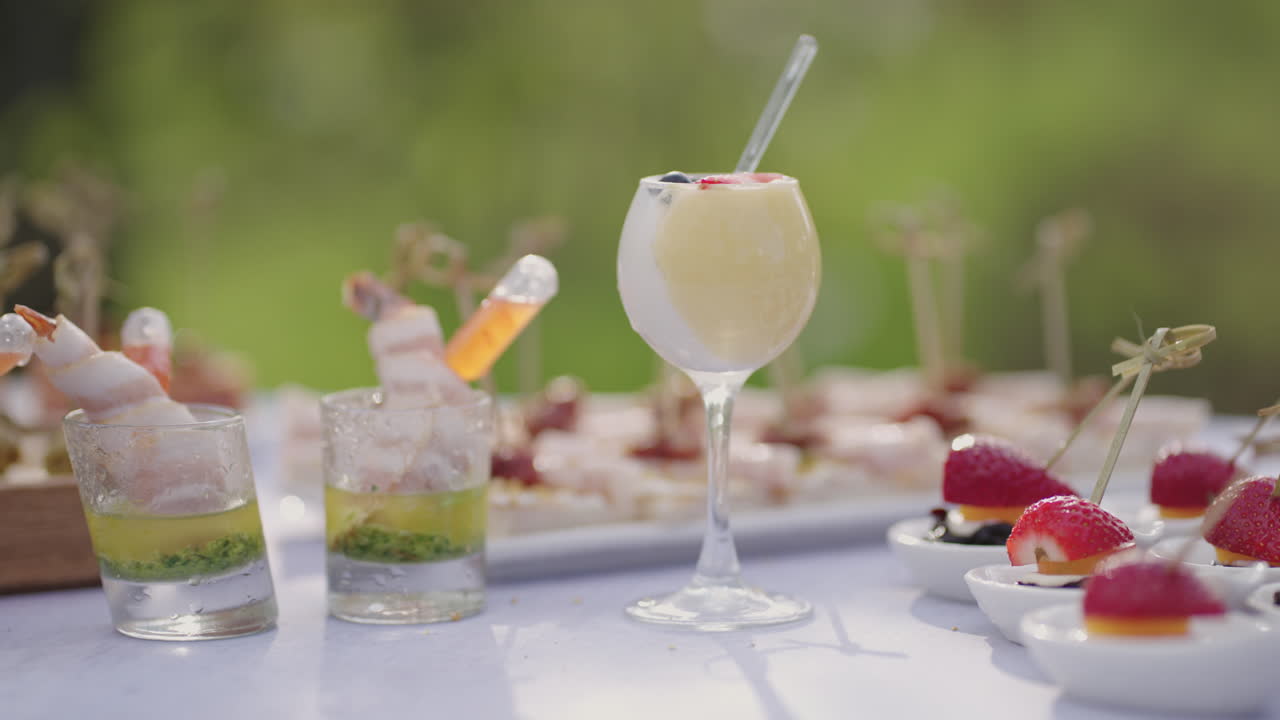 ⁇ 테일과 식구는 손가락 뷔페 야외에 컵과 맛있는 간식으로 테이블을 가 ⁇ 게