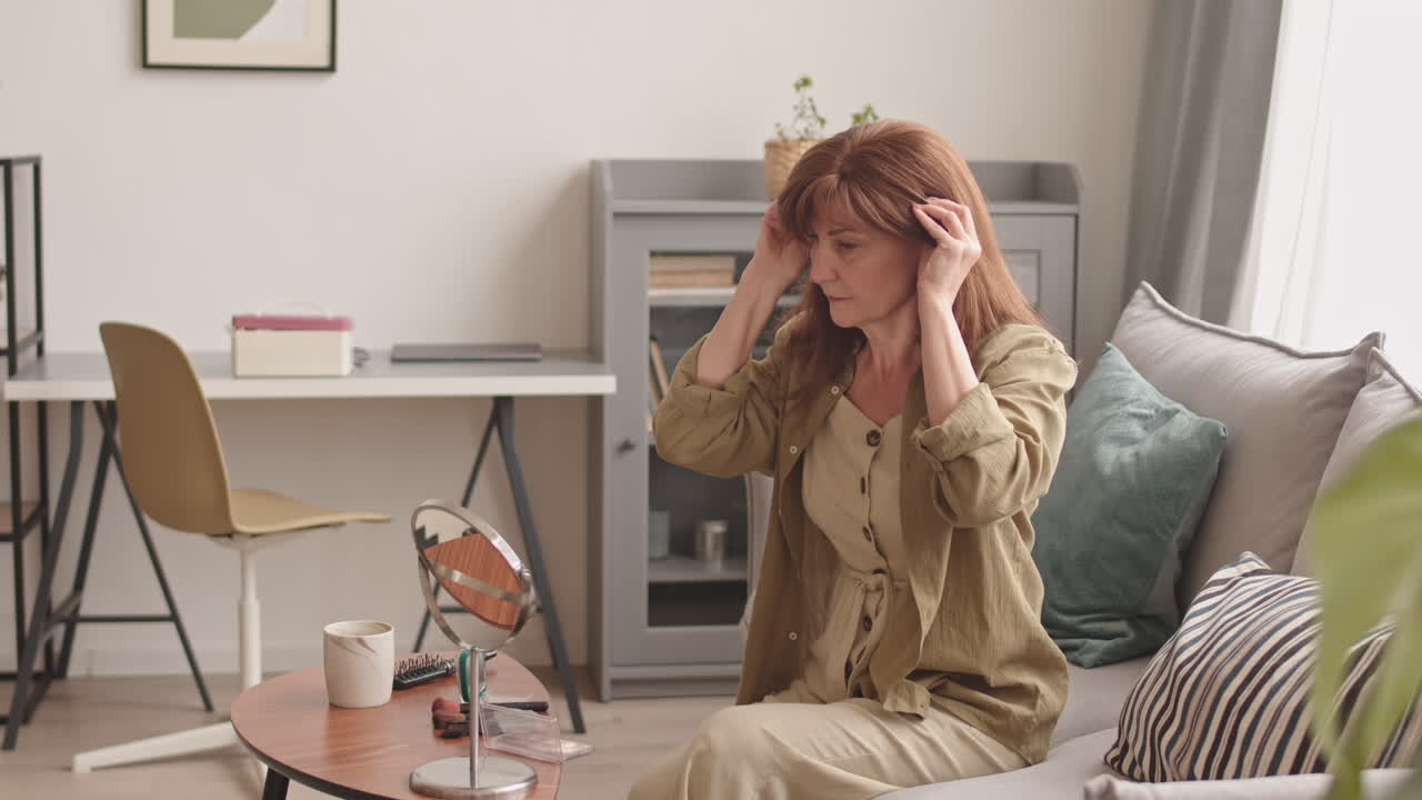 Hairless Woman Putting on Wig at Home